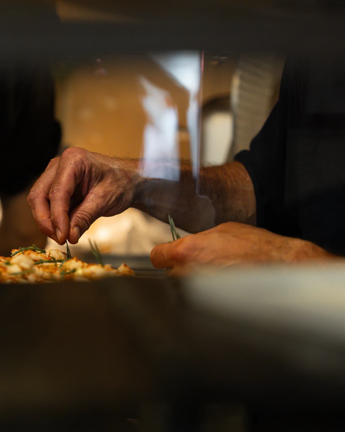 A chef adding finishing touches to a dish in a warmly lit kitchen
