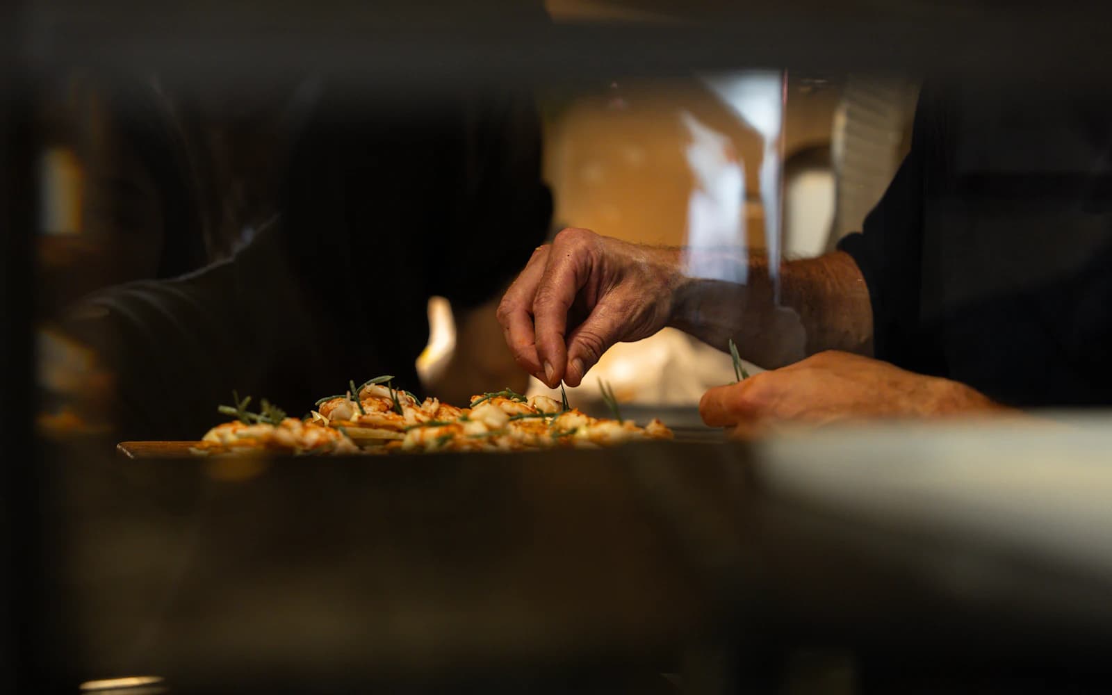 A chef adding finishing touches to a dish in a warmly lit kitchen