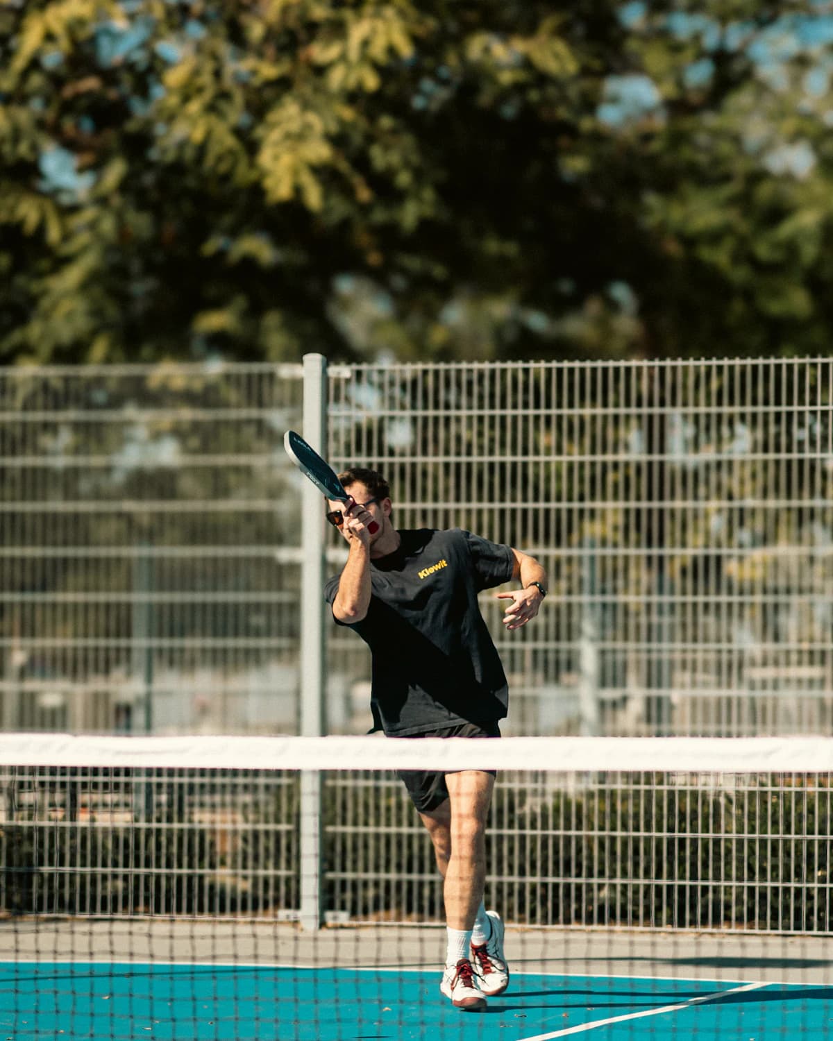 A player hitting a shot on an outdoor court on a sunny day