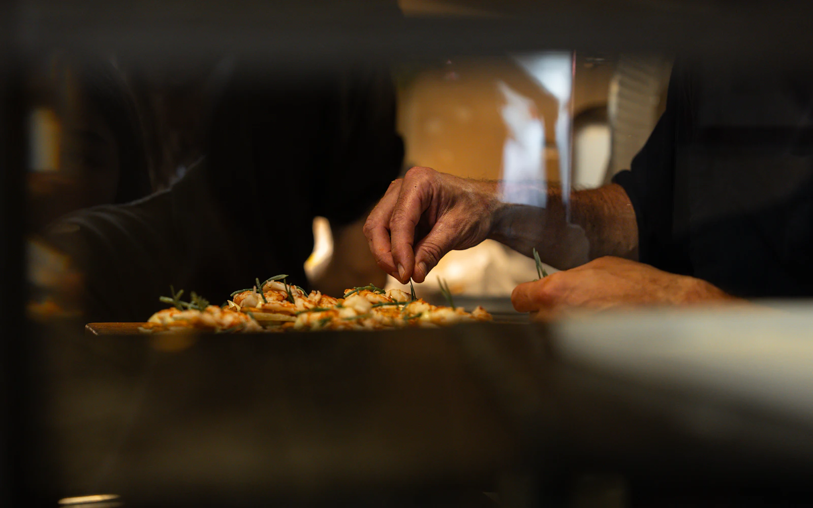 A chef adding finishing touches to a dish in a warmly lit kitchen