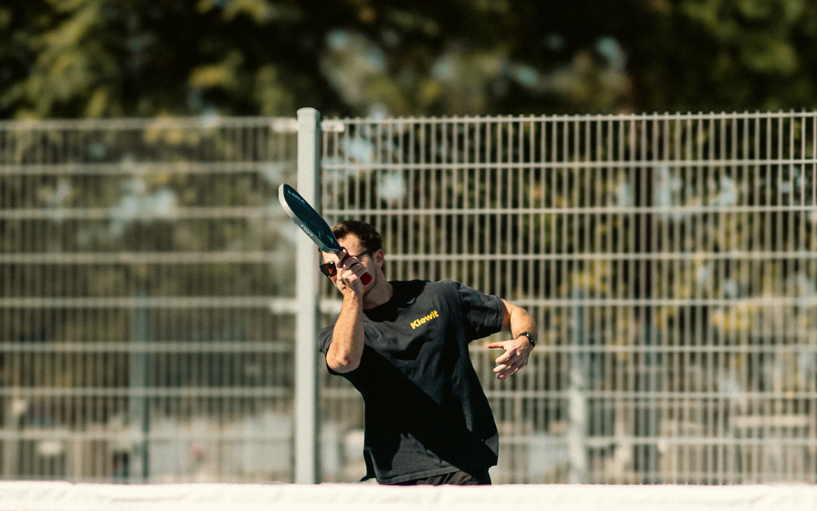 A player hitting a shot on an outdoor court on a sunny day